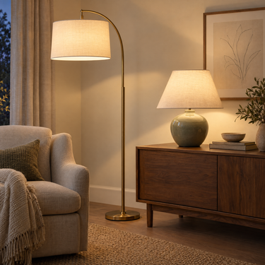 Brass arc floor lamp beside a sage green table lamp on a walnut console