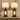 Closeup of black-gold lantern farmhouse pair — square to console, both lamps on, clean stems, gold rub-through.