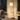 Seoul wood-tray floor lamp lit beside a quiet armchair in a living room, natural wood shelf readable.