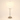 Brushed nickel table lamp with a clear glass cylinder and white fabric shade, lamp on
