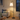 Same Seoul floor lamp beside a sofa, cream shade on, tall floor scale clear.