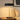 Black disc table lamp on a quiet wood nightstand, shade on