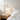 Globe table lamp on a light oak nightstand beside white linen bedding, lamp on