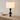 Stacked-disc table lamp on a light wood console with one ceramic bowl, shade on