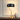 Gold curve table lamp on a console with one ceramic vase, shade on