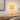 Ochre bobbin table lamp on a light wood desk with a book, shade on