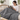 Woman reading on a sofa with the gray weighted throw blanket over her lap and legs