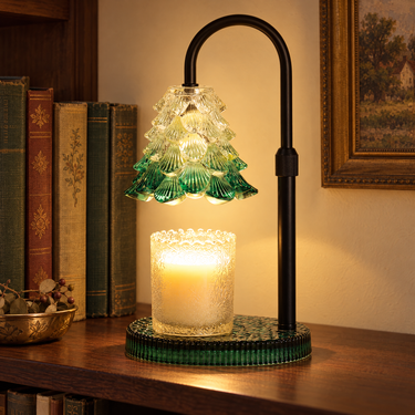 Green Glass Tree Candle Warmer Lamp glowing on a walnut shelf beside old books
