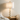 Stacked marble table lamp on an oak nightstand beside rumpled linen bedding, lamp on