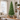 Slim green artificial Christmas tree in a bright living room