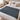 Dark grey knit weighted blanket laid flat across a bed with white and oatmeal bedding