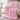 Pink knit weighted blanket thrown over an ivory armchair by a window
