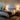 A pair of lit table lamps on nightstands flanking a bed with cream linen bedding