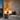 A lit ceramic table lamp on a side table beside a cream linen sofa at dusk