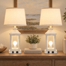 Closeup of distressed white wood lantern farmhouse pair — square to console, both lamps on, clean stems.