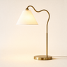 Brass ring table lamp with a single S-curve stem and white tapered shade, lamp on