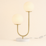 Dual globe table lamp with two frosted glass spheres on a brushed-brass U-stem and white disc, both globes on