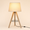 Light-wood tripod table lamp with a black metal ring and tapered cream shade, lamp on