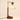 Dark wood post with a brass crane arm and cream cone shade, lamp on