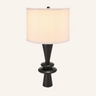 Matte black stacked-disc table lamp with a tall white fabric drum shade, lamp on