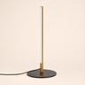 Slim vertical LED table lamp with gold housing and black disc base, lamp on
