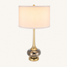 Smoky glass table lamp with a tall white drum shade, flared gold neck, and smoky mercury-glass orb, lamp on