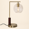 Brass L-neck table lamp with a dark wood collar and clear glass globe, lamp on