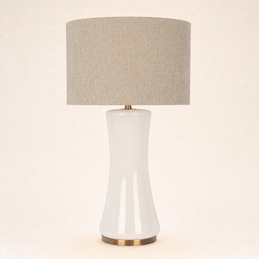 Off-white glass hourglass table lamp with a tan linen drum shade, lamp off
