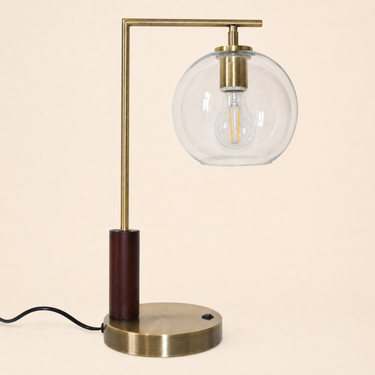 Brass L-neck table lamp with a dark wood collar and clear glass globe, lamp off