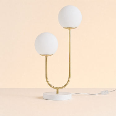 Dual globe table lamp with two frosted glass spheres on a brushed-brass U-stem and white disc, both globes off