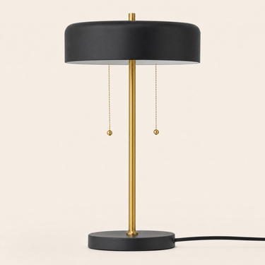 Black disc table lamp with a wide shallow black drum shade and gold stem, lamp off