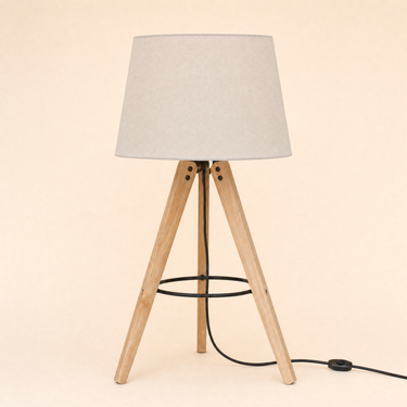 Light-wood tripod table lamp with a black metal ring and tapered cream shade, lamp off