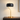 Gold curve table lamp on a quiet nightstand, shade on