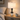 Geometric column table lamp on a pale oak nightstand, shade on