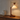Wood crane arm table lamp on a console with one ceramic vase, shade on