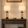 Pair of farmhouse table lamps on a console with one ceramic bowl, both lamps on