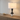 Geometric column table lamp on a light wood console with one ceramic bowl, shade on