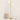 Gold two-globe tree floor lamp next to a chair for scale, lit