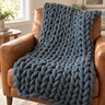 Dark grey chunky knit weighted blanket draped over a leather armchair