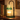 Green Glass Tree Candle Warmer Lamp glowing on a walnut shelf beside old books