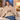 Woman on a sofa wearing the beige wearable heated blanket
