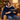 Woman reading in an armchair wearing the dark blue wearable heated blanket