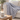 Grey knit weighted blanket draped over the arm of a cream sofa